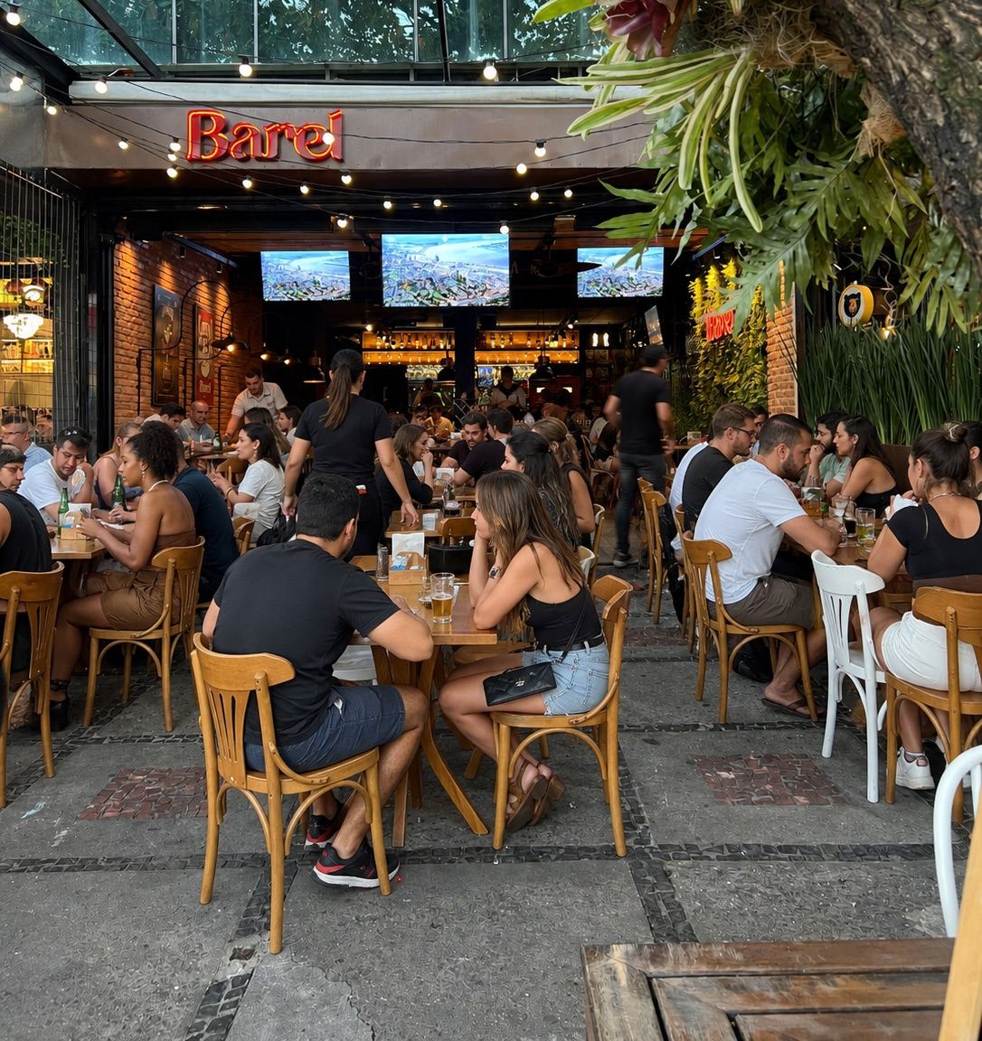 Fachada do Barel na Barra da Tijuca com as mesas da calçada cheias no fim da tarde